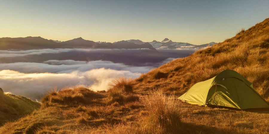 Tent on mountain above cloud line 