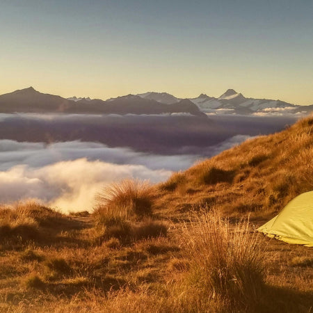 Tent on mountain above cloud line 