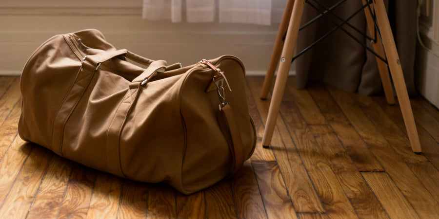 Closed tan duffel bag on wood floor